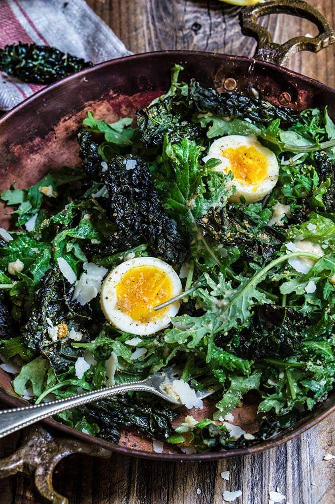 Kale salad with low fat Caesar dressing - baby kale and roasted kale chips, garlicky bread crumbs, and soft boiled eggs, drizzled with a healthy Caesar dressing which is packed with protein, low in fat, yet creamy and robust in flavor. | www.viktoriastable.com