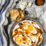 Eggs in garlicky yogurt - crispy fried egg whites and soft yolks, drizzled with butter paprika sauce, and served over a bed of cold, creamy garlicky yogurt - this is the ultimate egg dish to dig in with a piece of toasted bread! | www.viktoriastable.com